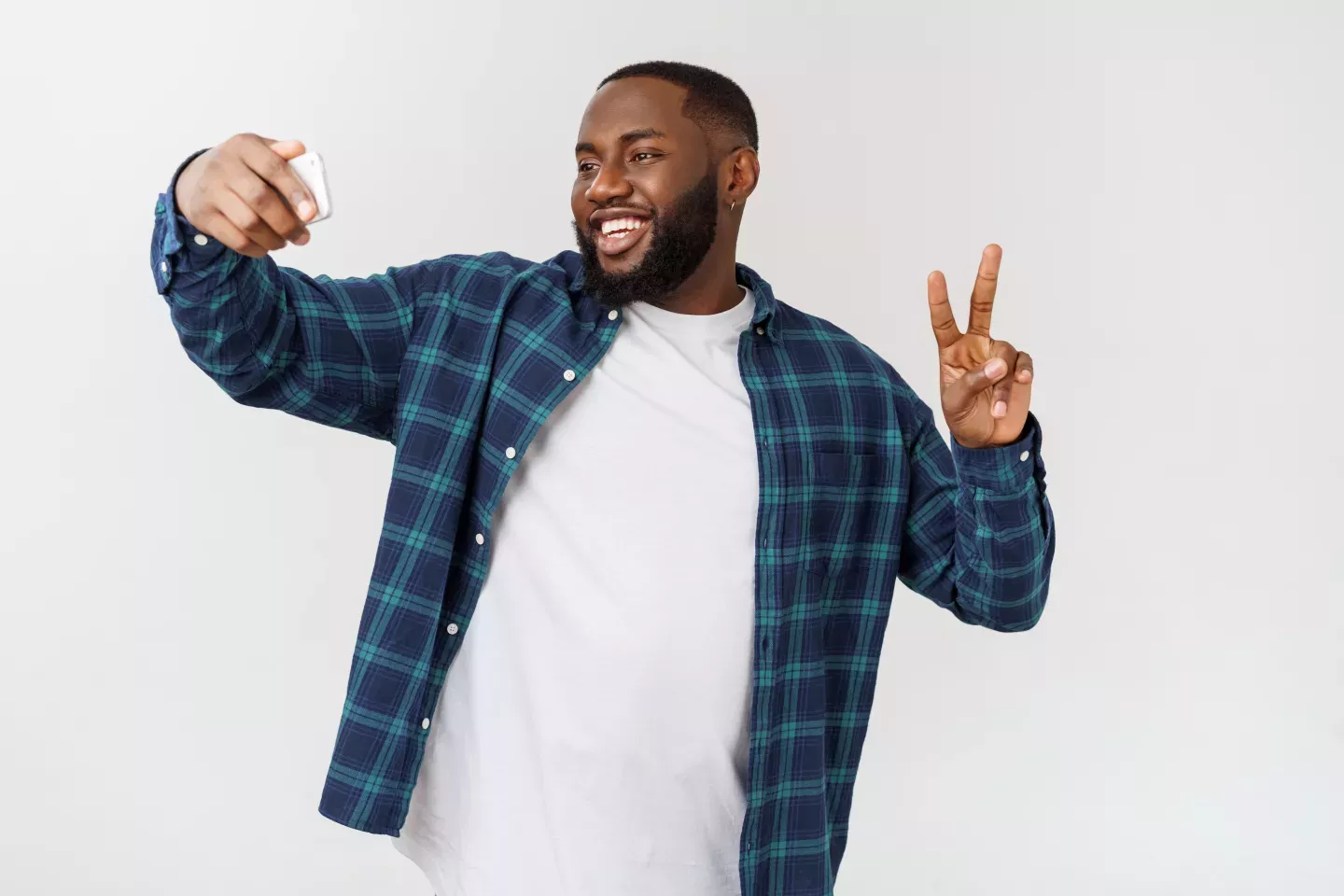man taking selfie holding up hand to make a peace sign