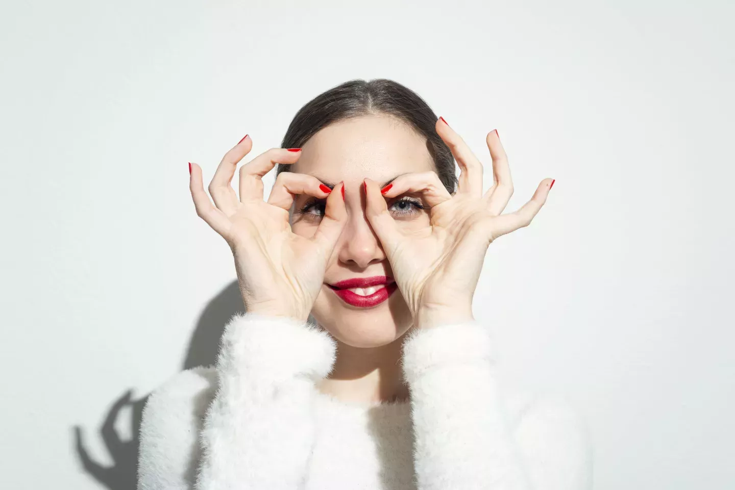 woman holding hands over eyes peeking through fingers