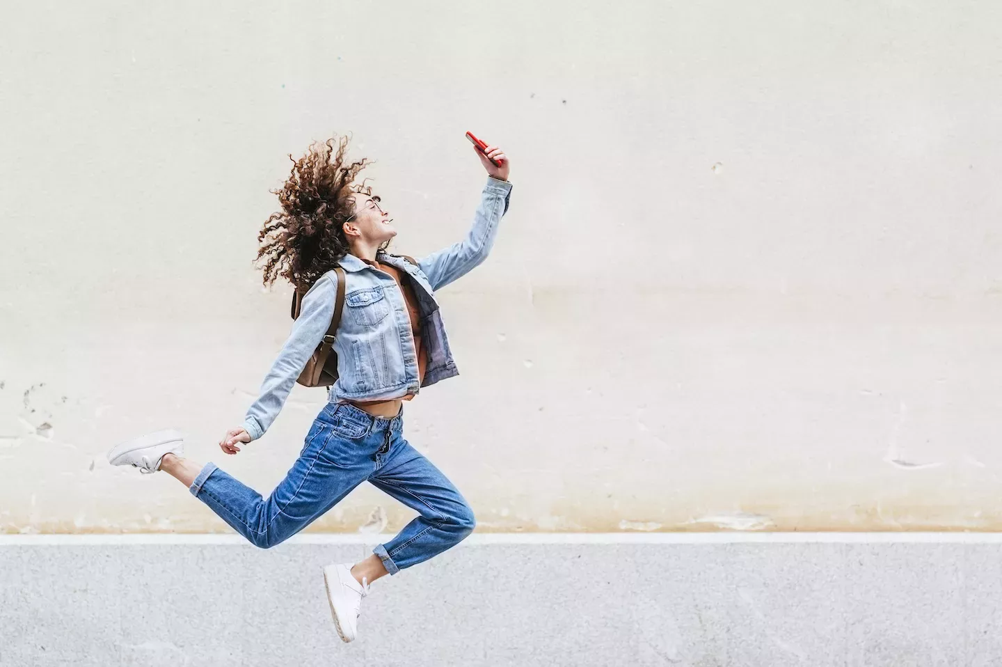 Woman jumping looking at a phone