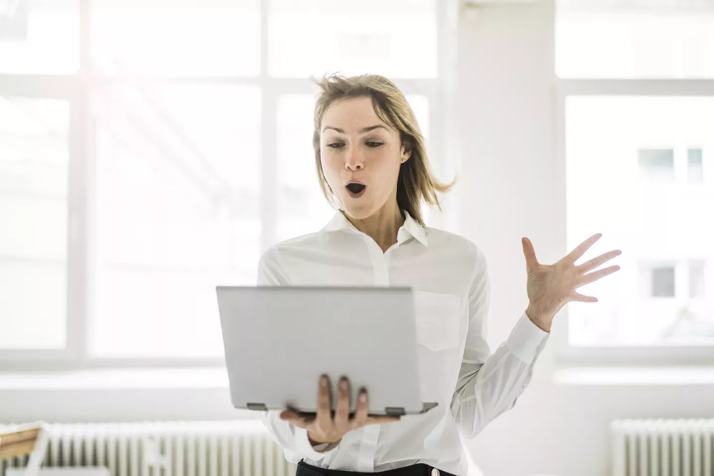 Woman with hair blowing in the wind looking at laptop