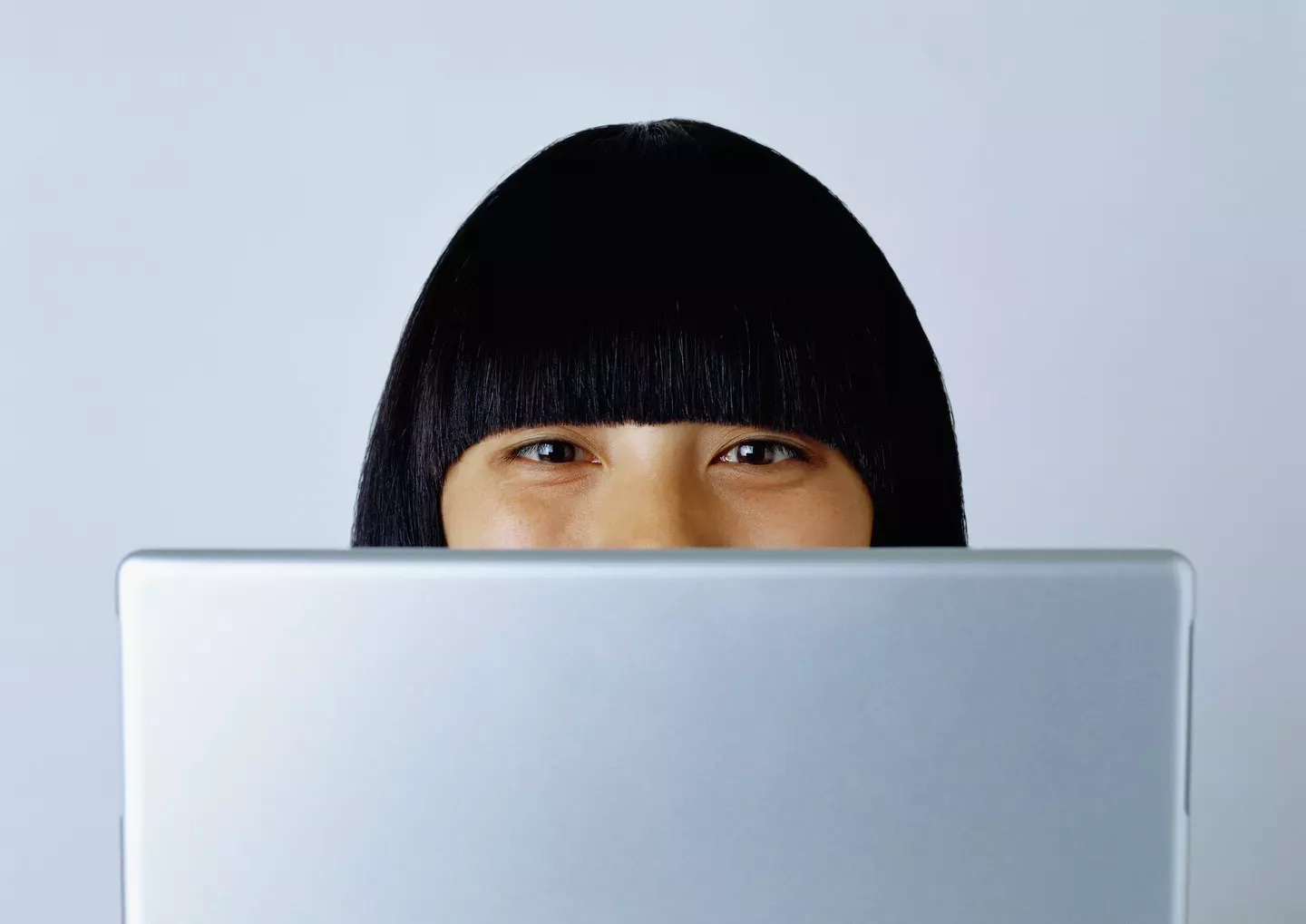 Woman looking over the top of her laptop