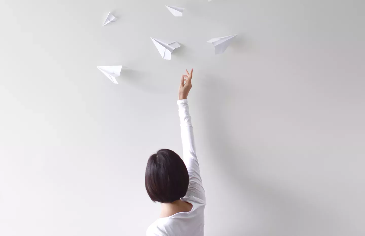 Woman reaching for paper planes Woman reaching for paper planes