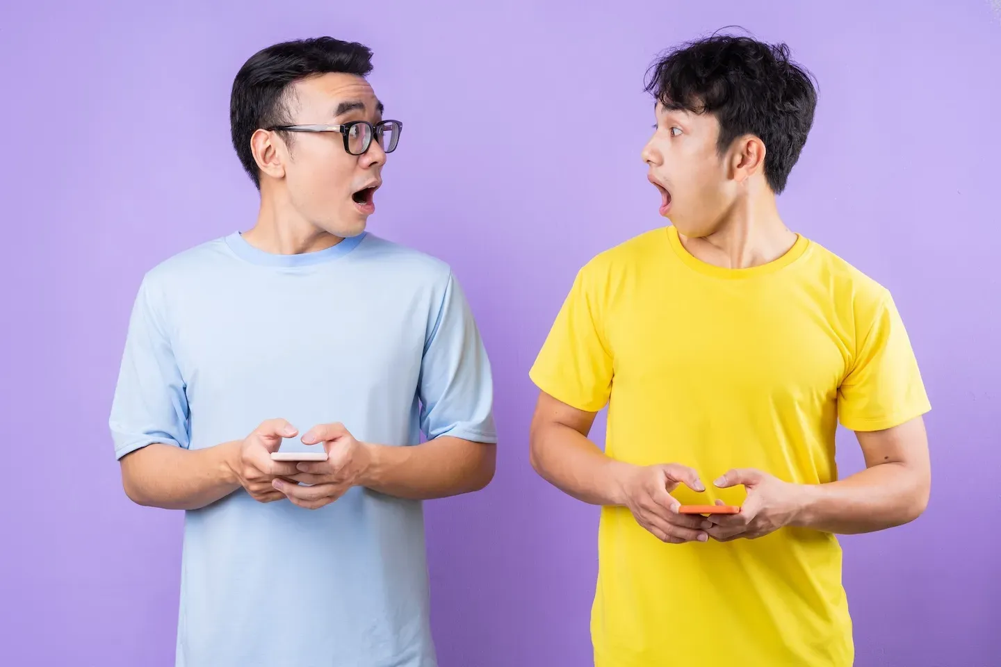 twins on their cell phones looking at each other in shock