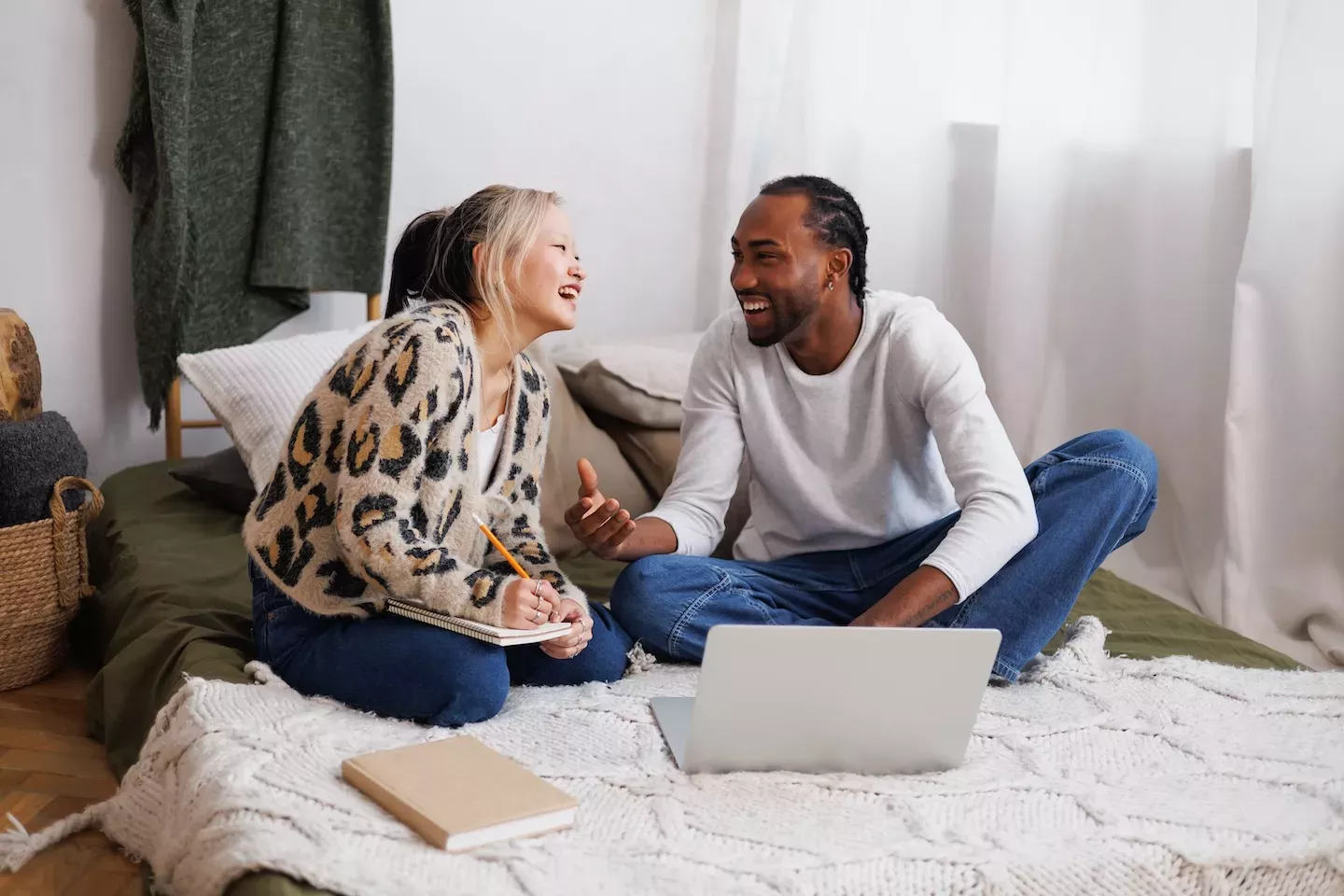 Couple smiling at each other looking at laptop