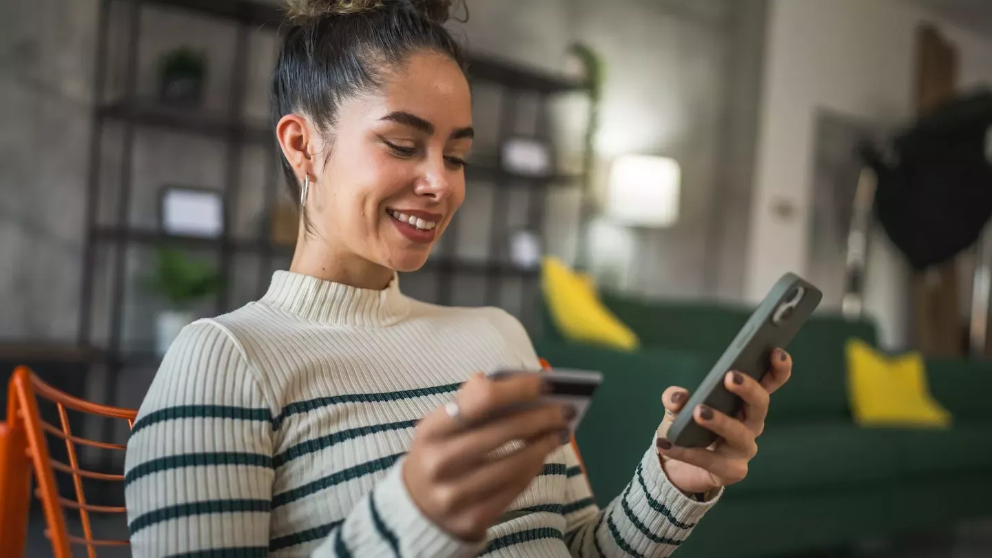 smiling woman making purchase on cell phone smiling woman making purchase on cell phone