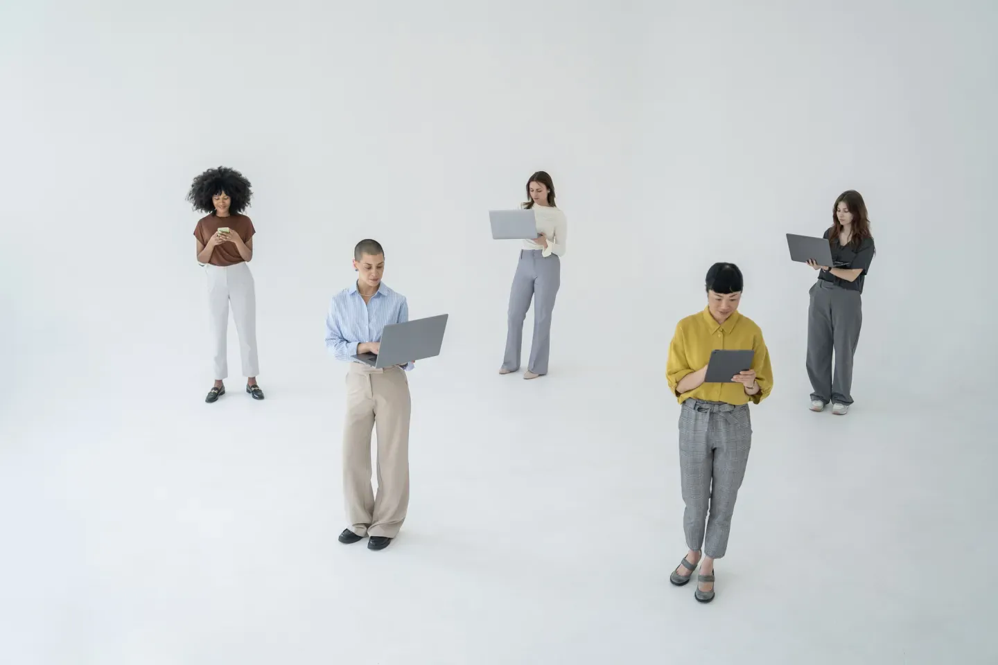 Five small figurines of people in casual clothing scattered on white background