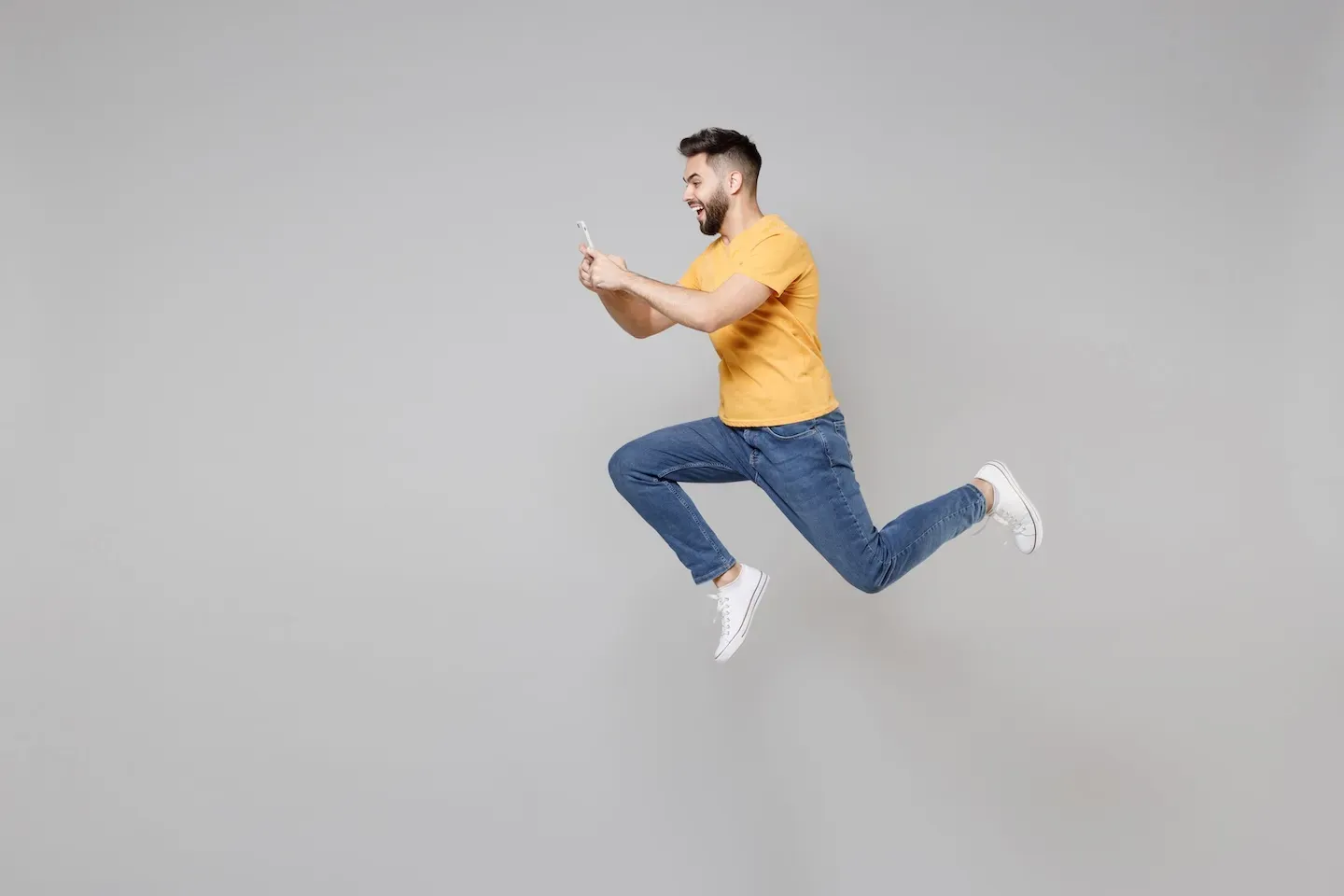 smiling man leaping and holding cell phone