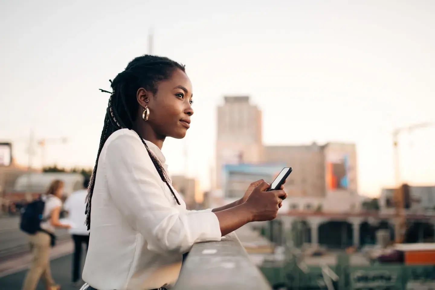 Woman looking at city skyline holding phone Woman looking at city skyline holding phone